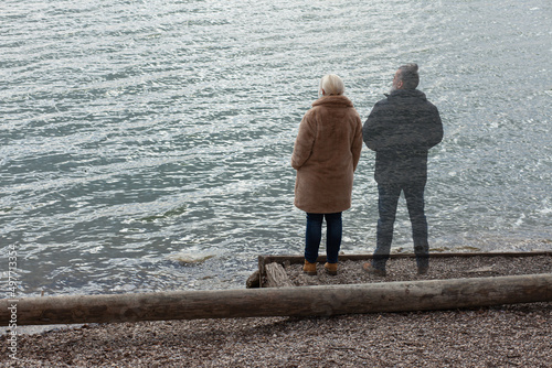 Lonely woman standing by the lake with ghost of a man standing by her side, staring in the distance