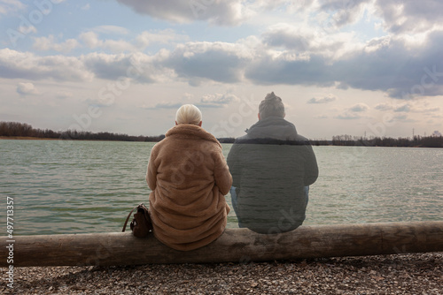 Lonely woman sitting by the lake with ghost of a man sitting by her side, staring in the distance