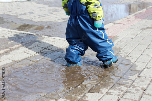 a child in a raincoat and rubber boots walks through puddles on a walk plays walks hooligans has fun © Татьяна Фоевцева