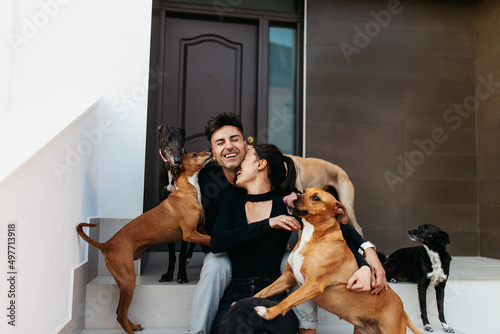 Canvas Print Couple having fun with their playful dogs at home