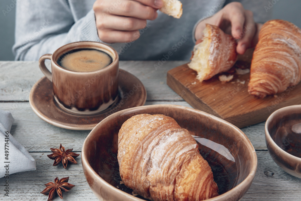 The girl drinks coffee and eats croissants. Fragrant stimulating drink. Fresh bakery. Breakfast, snack.