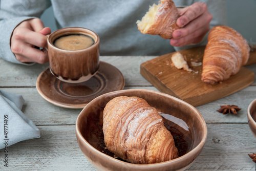 The girl drinks coffee and eats croissants. Fragrant stimulating drink. Fresh bakery. Breakfast, snack.