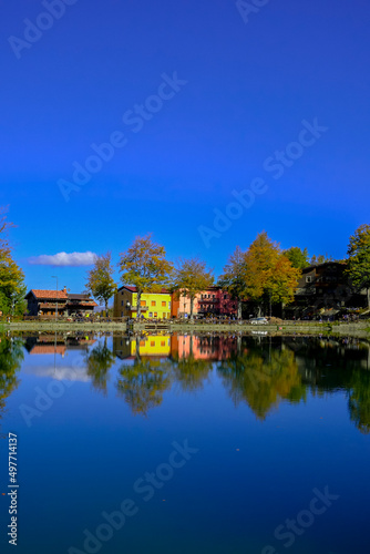 Colorful houses on the lake on a sunny bright day. Water reflections. Landscape background. Cerreto Laghi, Reggio Emilia, Italy. Travel 
