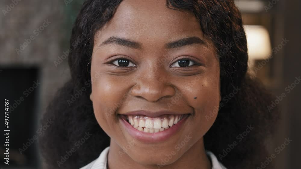Extreme close up female face with perfect skin healthy millennial african woman looking at camera indoors happy 20s 30s girl with white toothy smile in apartment smiling casual model posing portrait Extreme close up female face with perfect skin healthy millennial african woman looking at camera indoors happy 20s 30s girl with white toothy smile in apartment smiling casual model posing portrait