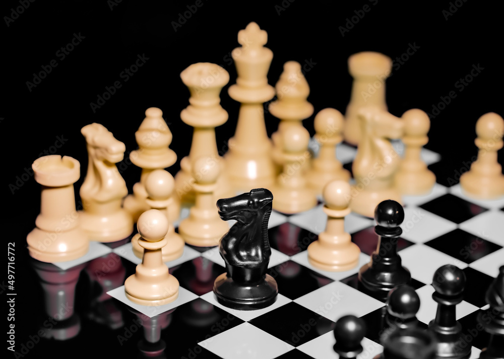 Close up of Chess pieces on a reflective mirror board surface with black background Close up of Chess pieces on a reflective mirror board surface with black background