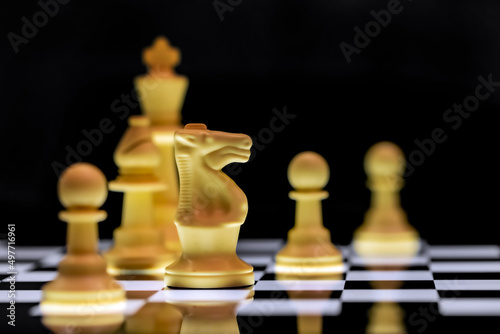 Close up of Chess pieces on a reflective mirror board surface with black background