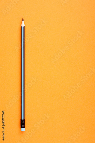 Black and blue pencil on orange background with empty copy space for text. photo
