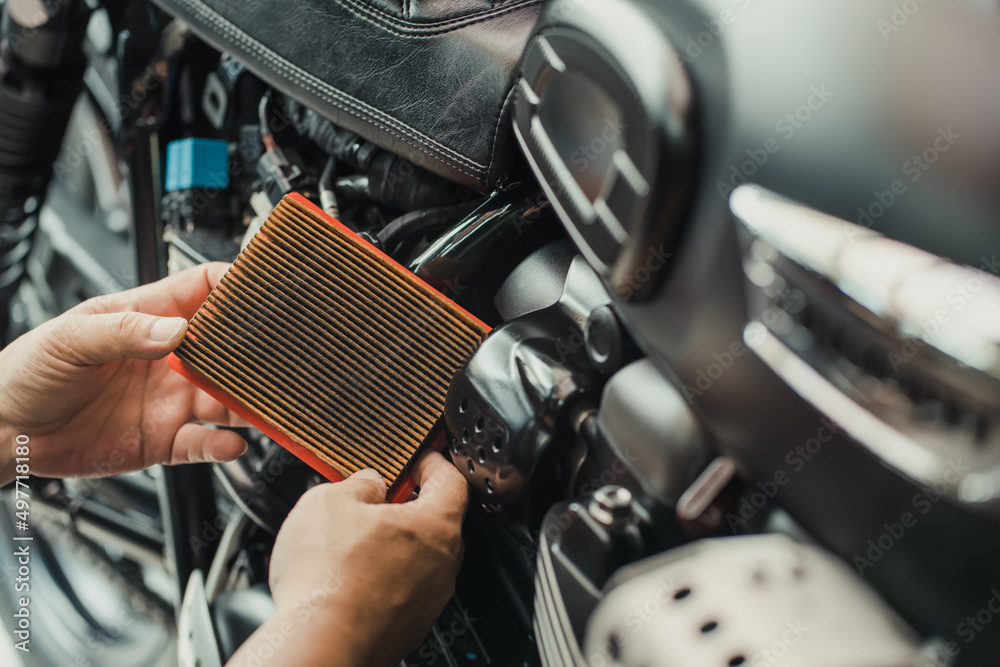 mechanic holding dirty Engine Air Filter over motorcycle, scooter .mechanic working in garage. Repair and maintenance motorcycle concept