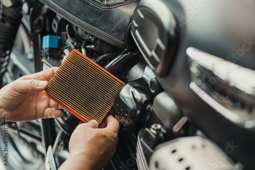 Obraz na płótnie mechanic holding dirty Engine Air Filter over motorcycle, scooter .mechanic working in garage. Repair and maintenance motorcycle concept w salonie