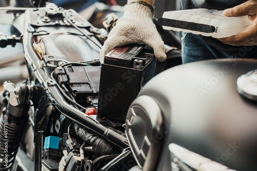  mechanic replaces motorcycle battery and holding Acid pack or sealed battery electrolyte pack to prepare for fill up battery,motorcycle maintenance and service and repair concept . selective focus
