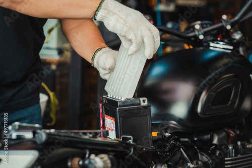 mechanic replaces motorcycle battery and holding Acid pack or sealed battery electrolyte pack to prepare for fill up battery,motorcycle maintenance and service and repair concept . selective focus