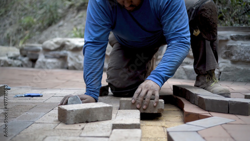 Принти на полотні Closeup of hand putting brick paver into place in a hardscaping project