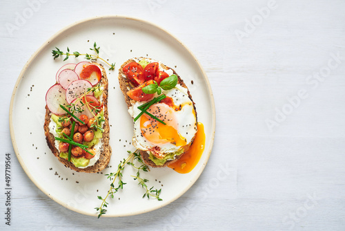 Vegetarian egg sandwiches on white background.. Healthy vegetarian sandwiches with egg tomatoes avocado cream and cheese garnished with chia seeds and aromatic herbs. Vegetarian sandwich.