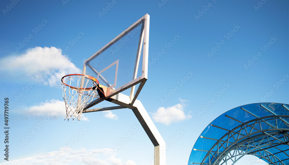 Side view of a basketball hoop with a backboard on a sports field, against a blue sky. Achievement, sports concept Side view of a basketball hoop with a backboard on a sports field, against a blue sky. Achievement, sports concept
