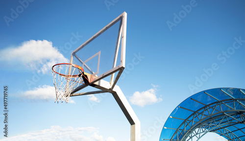 Side view of a basketball hoop with a backboard on a sports field, against a blue sky. Achievement, sports concept photo