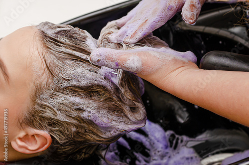 Hair stylist applying coloring purple shampoo after hair dyeing. Close up.