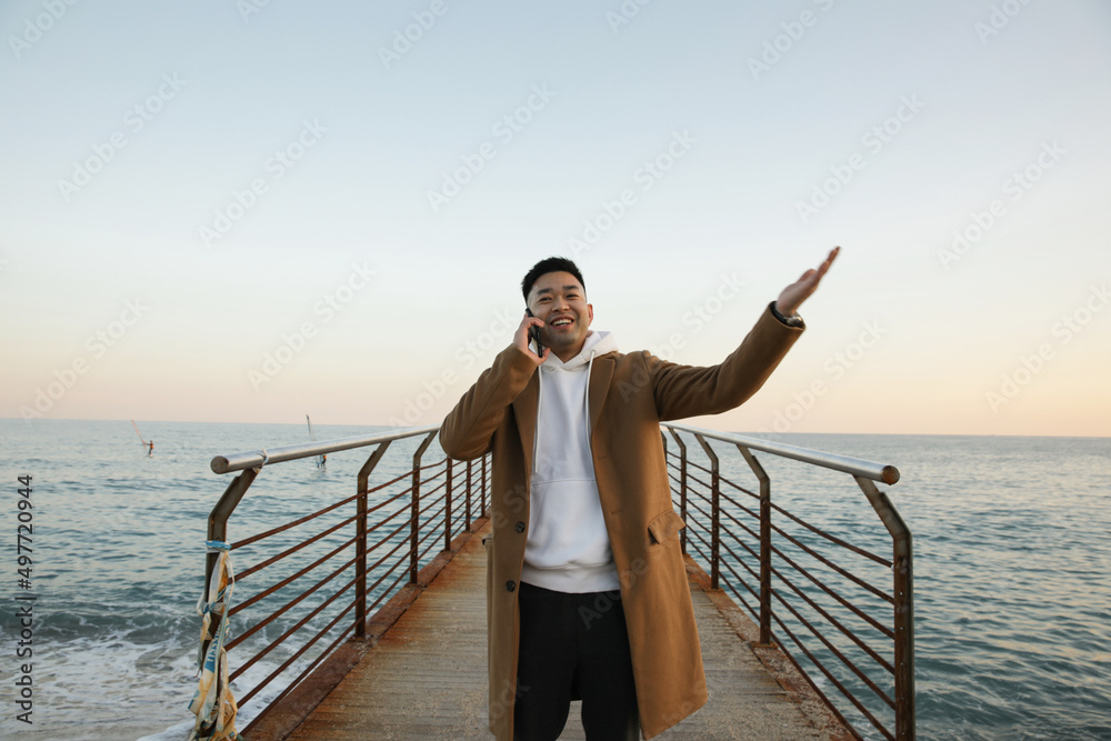 Portrait of relaxed young Asian man using smartphone on the beach. Freelance.