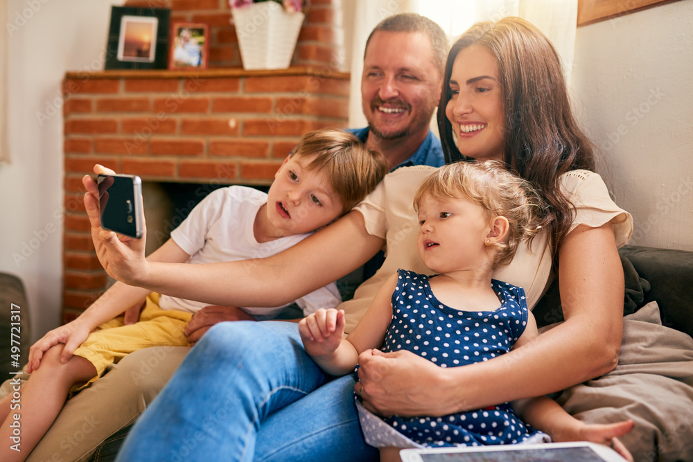 The most important memories made are those with family. Shot of a happy young family taking a selfie together on the sofa at home.