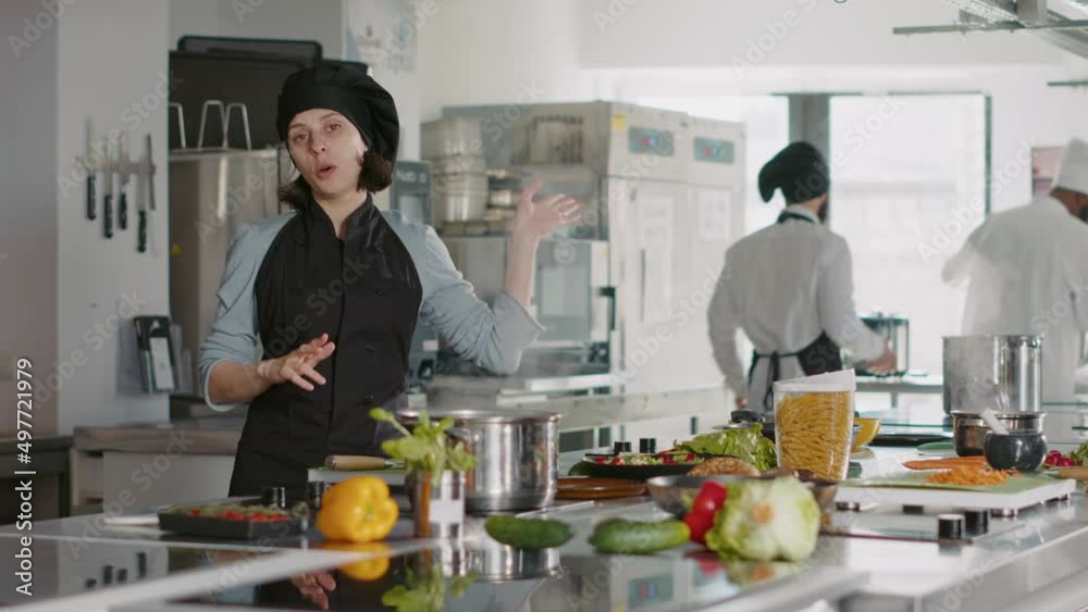 POV of professional cook making cooking show content with food in restaurant kitchen, filming vlog on camera. Authenic woman in uniform doing meal preparations for gastronomy program. Tripod shot. POV of professional cook making cooking show content with food in restaurant kitchen, filming vlog on camera. Authenic woman in uniform doing meal preparations for gastronomy program. Tripod shot.