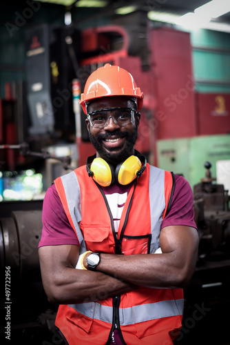 Foto portrait of Happy african-american man worker have unkempt beard in safety uniform wearing helmet,glasses, vest and glove in industrial manufacturer factory
