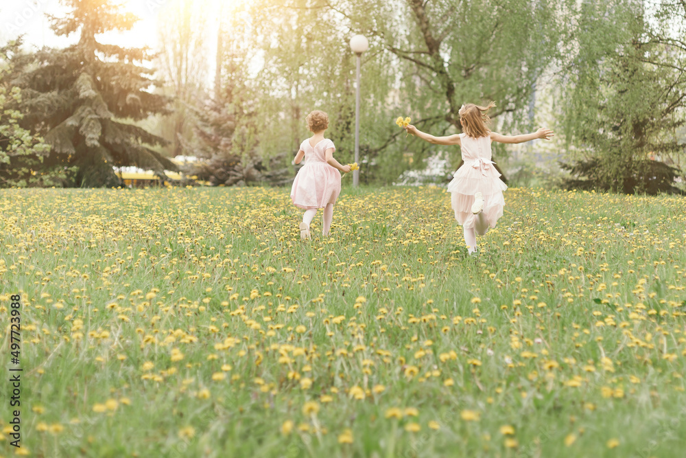 two little sisters running across the lawn on a spring day . two little sisters running across the lawn on a spring day .