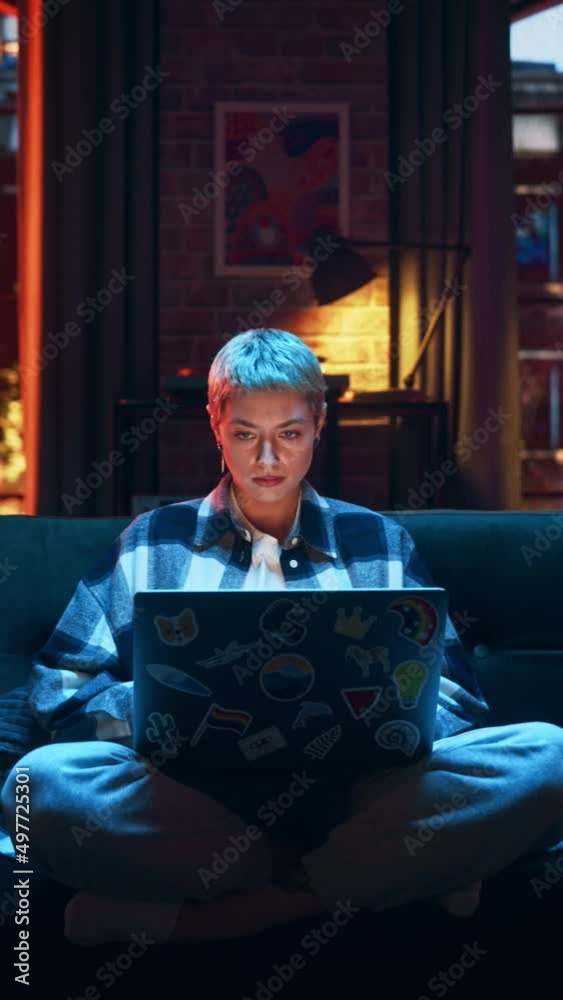 Vertical Screen: Young Woman Working from Home on Laptop Computer with Stickers in Cozy Stylish Loft Apartment. Creative Female Smiling, Checking Social Media, Browsing Internet.