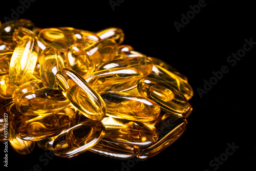 Close up of Omega 3 gel capsule on a reflective black background