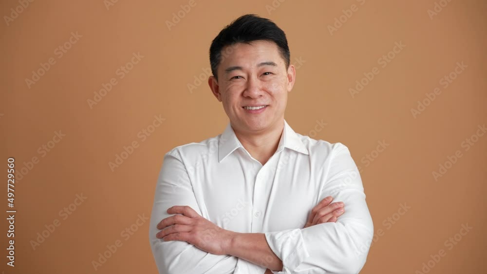 Smiling Asian man wearing white shirt looking at the camera in the orange studio Smiling Asian man wearing white shirt looking at the camera in the orange studio