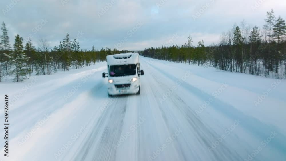 Campervan Driving Through Winter Landscape Between The Forest In Lapland, Finland. - aerial forward Campervan Driving Through Winter Landscape Between The Forest In Lapland, Finland. - aerial forward