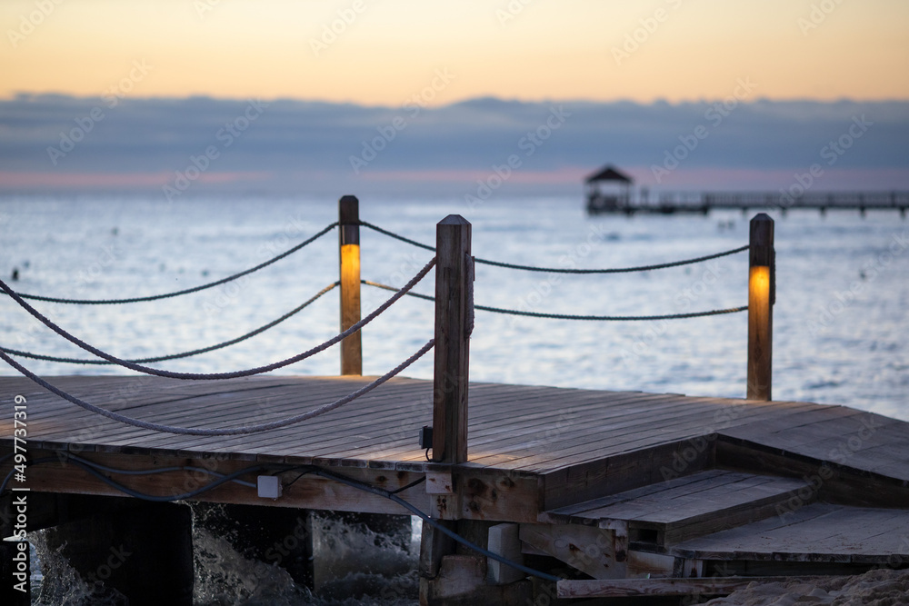 Sunset on the Caribbean coast in the Dominican Republic.Tourism,travel,recreation,background.Beautiful landscape of the sea coast.Wooden poles and rope railings of the pier, lights included close-up