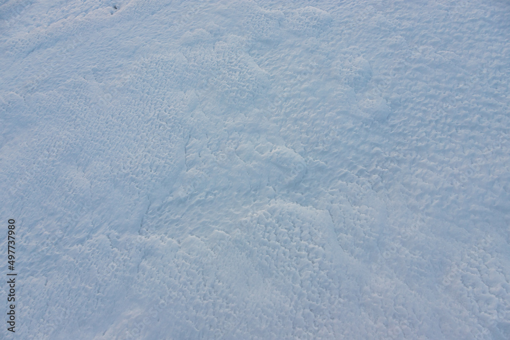Beautiful winter background with snowy ground. Natural snow texture. Wind sculpted patterns on snow surface Beautiful winter background with snowy ground. Natural snow texture. Wind sculpted patterns on snow surface