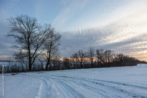 Natural sunset sunrise over field or meadow. The color of the sky over the winter snowy ground. Landscape under a picturesque sky at sunset. Dawn of the sun.