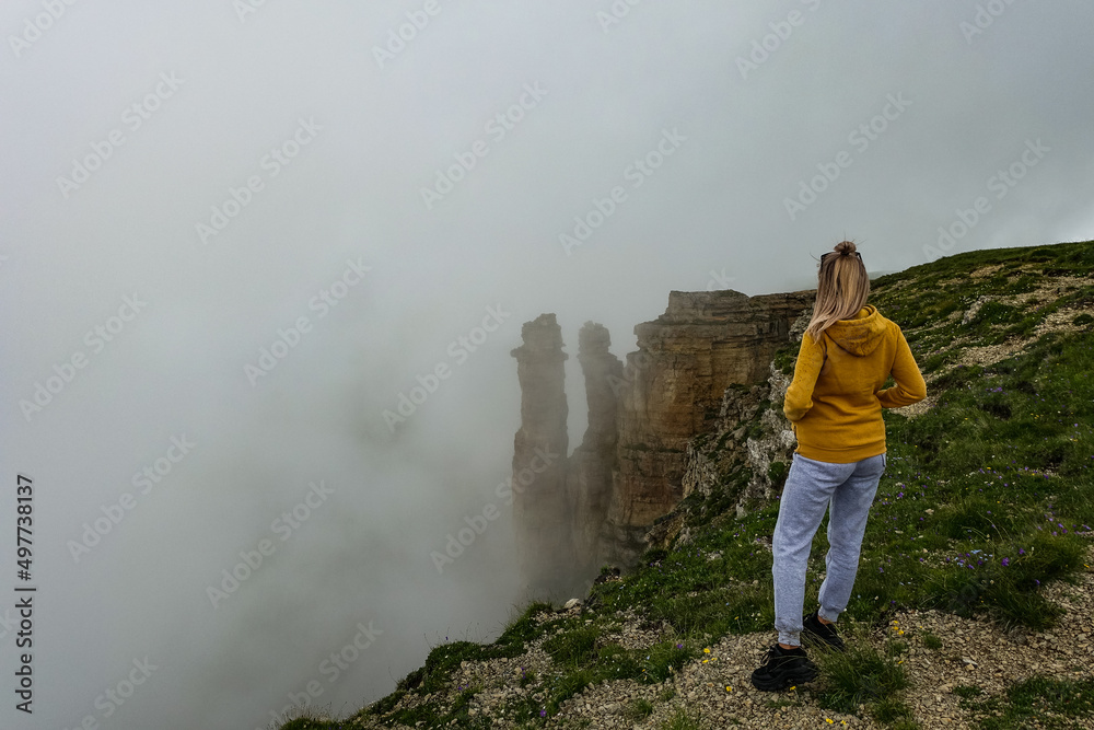 A girl on the background of two monks rocks in a cloud, Bermamyt plateau, Karachay-Cherkess Republic A girl on the background of two monks rocks in a cloud, Bermamyt plateau, Karachay-Cherkess Republic