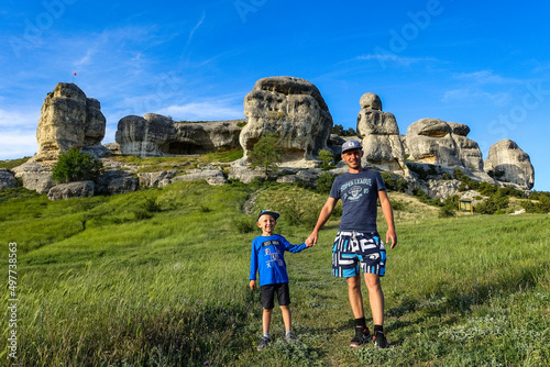 A man and a little boy on the background of a picturesque view of the Bakhchisarai sphinxes. Bakhchisarai. May 2021. photo