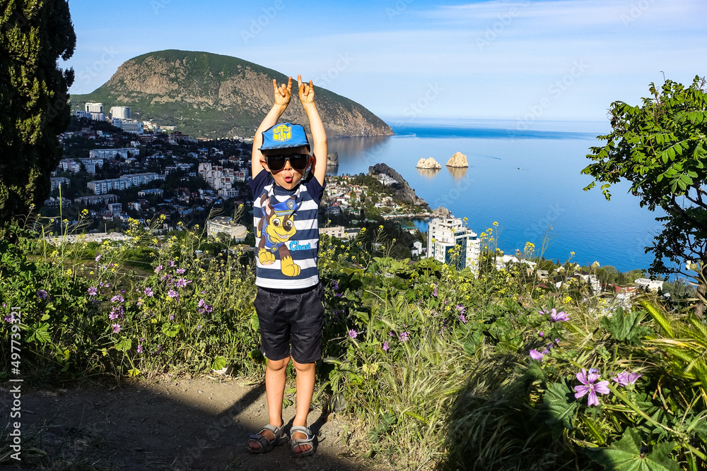 A boy on the background of a view of the Ayu-Dag mountain and the city of Gurzuf. May 2021.