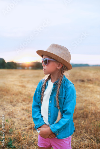 funny little girl with pigtails in sunglasses and straw hat outdoor in summer day. Summertime