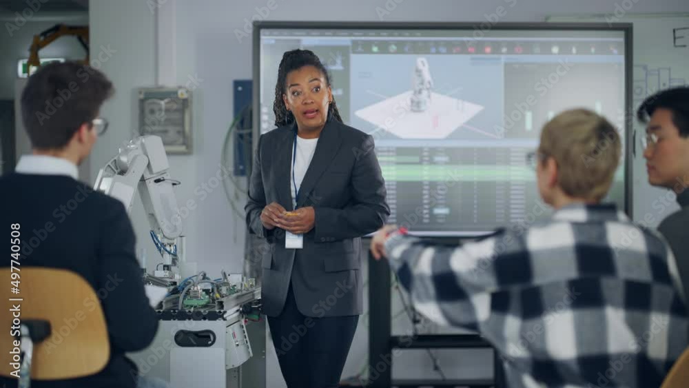 Black Teacher Asking at Students Questions and Pointing at Robotic Hand while Explaining During Lesson. Smart Girl Showing with Hand at Robot. Engineering and Programming Language Concept. Slow Motion