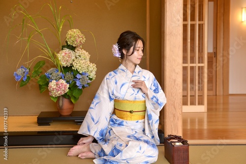 畳の上に座りポーズをとる浴衣姿の若く美しい女性