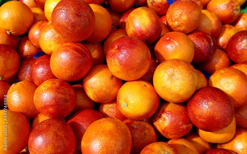 Heap of red blood oranges under the sunlight in the market stall.