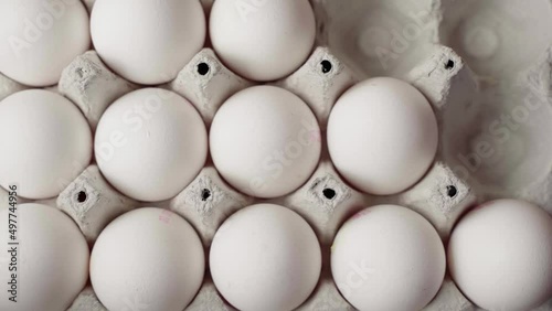 Hand laying out chicken eggs in a cardboard tray, top view