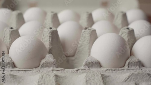 Hand picks up chicken eggs from a cardboard tray, side view