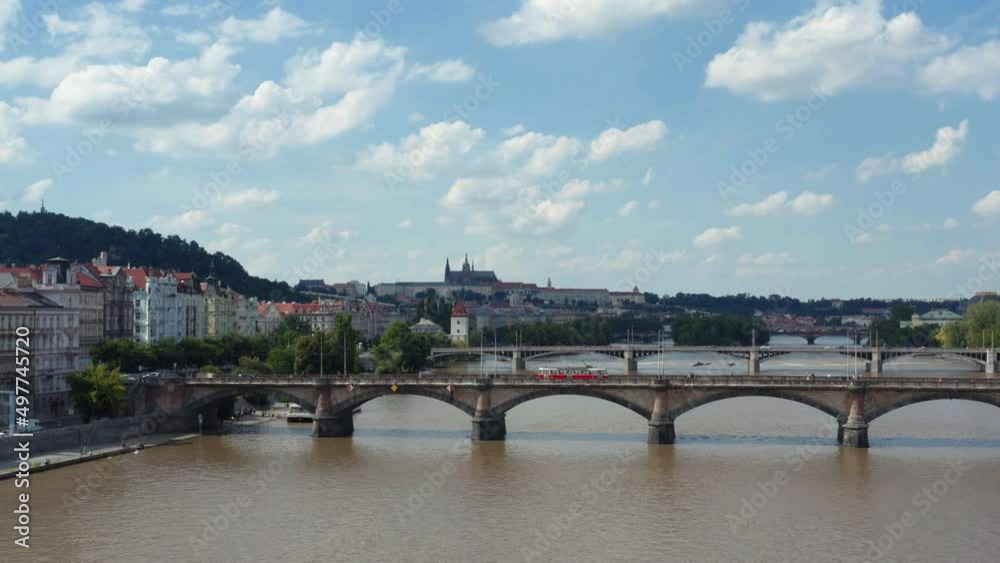 Silhouetted St. Vitus Cathedral dominates a cloudy Prague city skyline above the Vltava River, aerial Silhouetted St. Vitus Cathedral dominates a cloudy Prague city skyline above the Vltava River, aerial