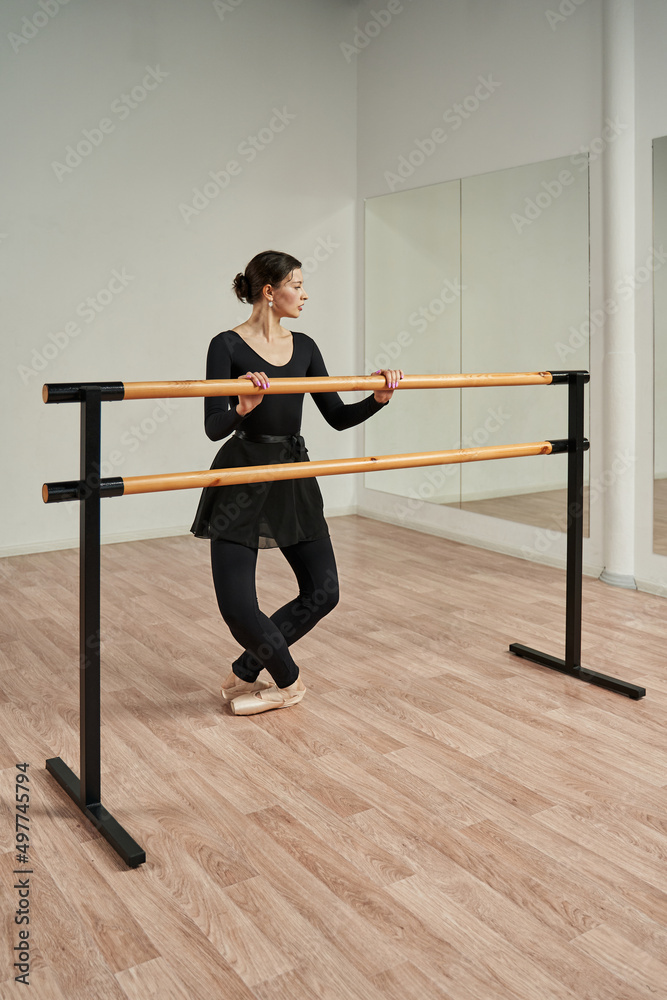 a ballerina in a dance class holds her hands on a ballet barre and looks at herself in the mirror a ballerina in a dance class holds her hands on a ballet barre and looks at herself in the mirror