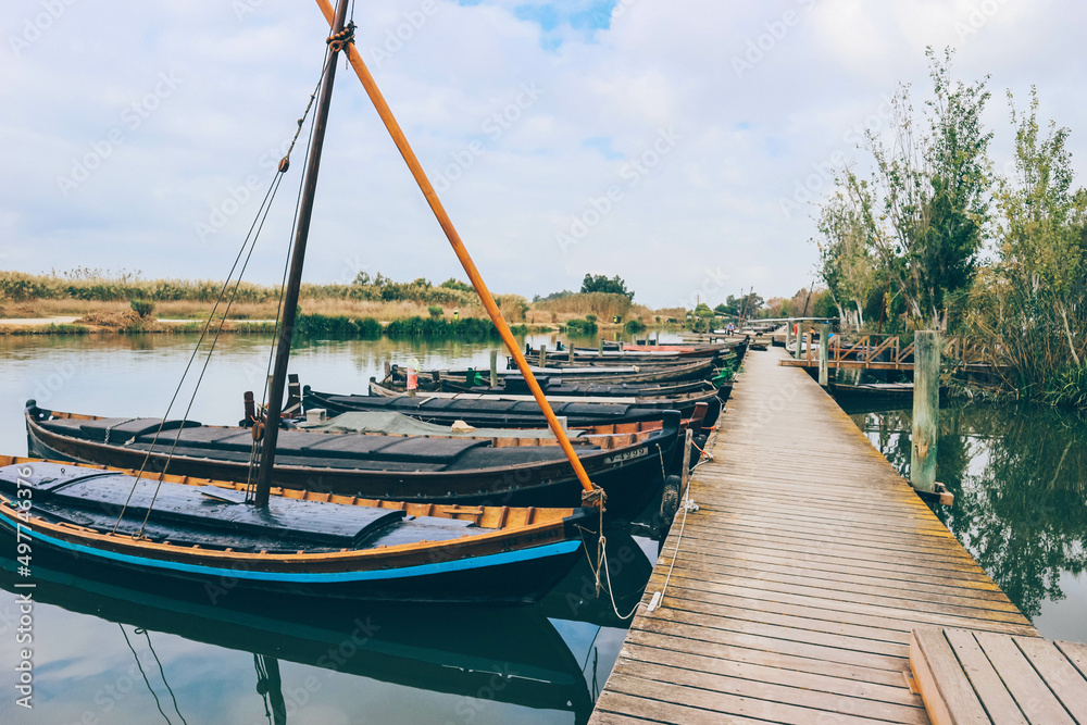 Traditional Valencian fisherman river port with manual sailboats and diverse nature behind 