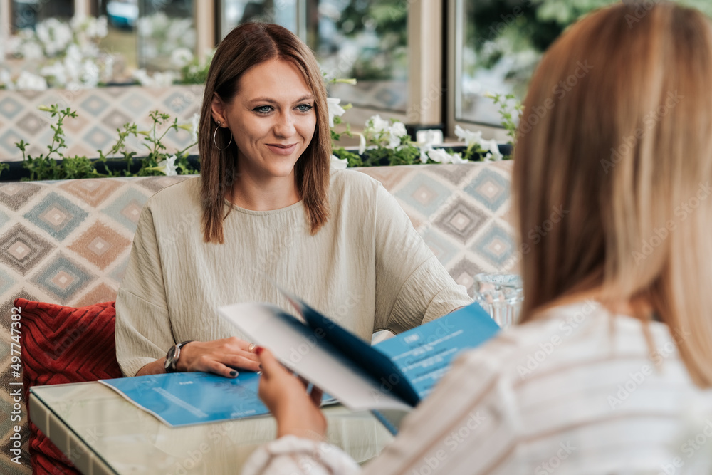 Two Women Sitting in Restaurant and Reading the Menu, Females on Lunch Meeting Two Women Sitting in Restaurant and Reading the Menu, Females on Lunch Meeting
