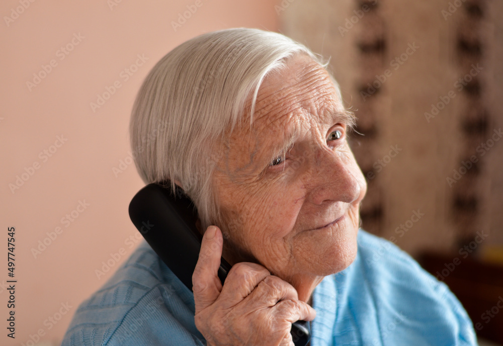 Fototapeta premium close-up of a 90-year-old elderly retired woman who is talking smiling on the phone.