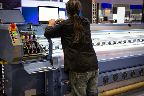 Industrial technician operating wide format digital inkjet printer. Printing industry.