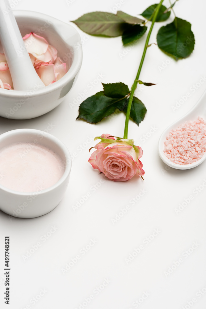 flower near pink sea salt, bowl with cream, pestle and mortar with petals on white. flower near pink sea salt, bowl with cream, pestle and mortar with petals on white.