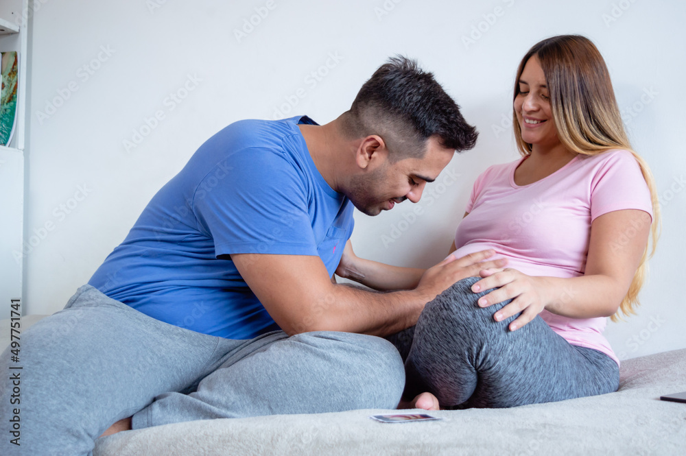 man lying in bed watching and touching his pregnant belly wife man lying in bed watching and touching his pregnant belly wife