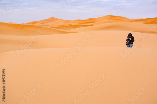 persona che cammina nelle dune di sabbia in mezzo al  deserto 